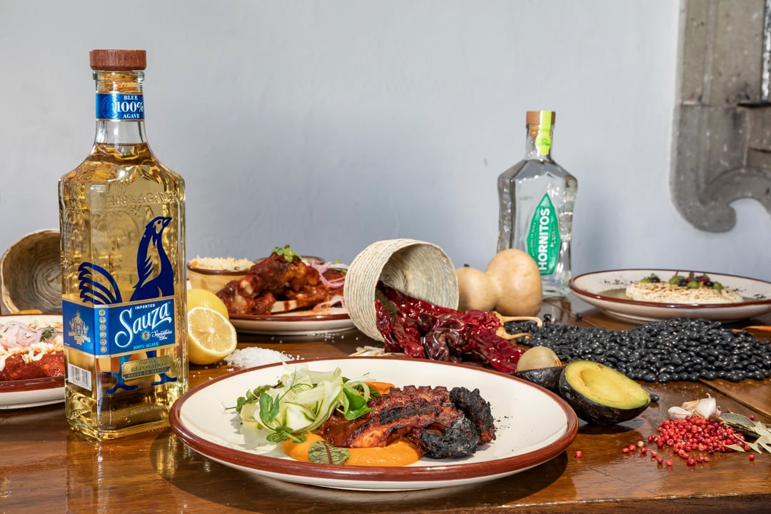 platillo en mesa con tequilas e ingredientes sauza reposado y hornitos